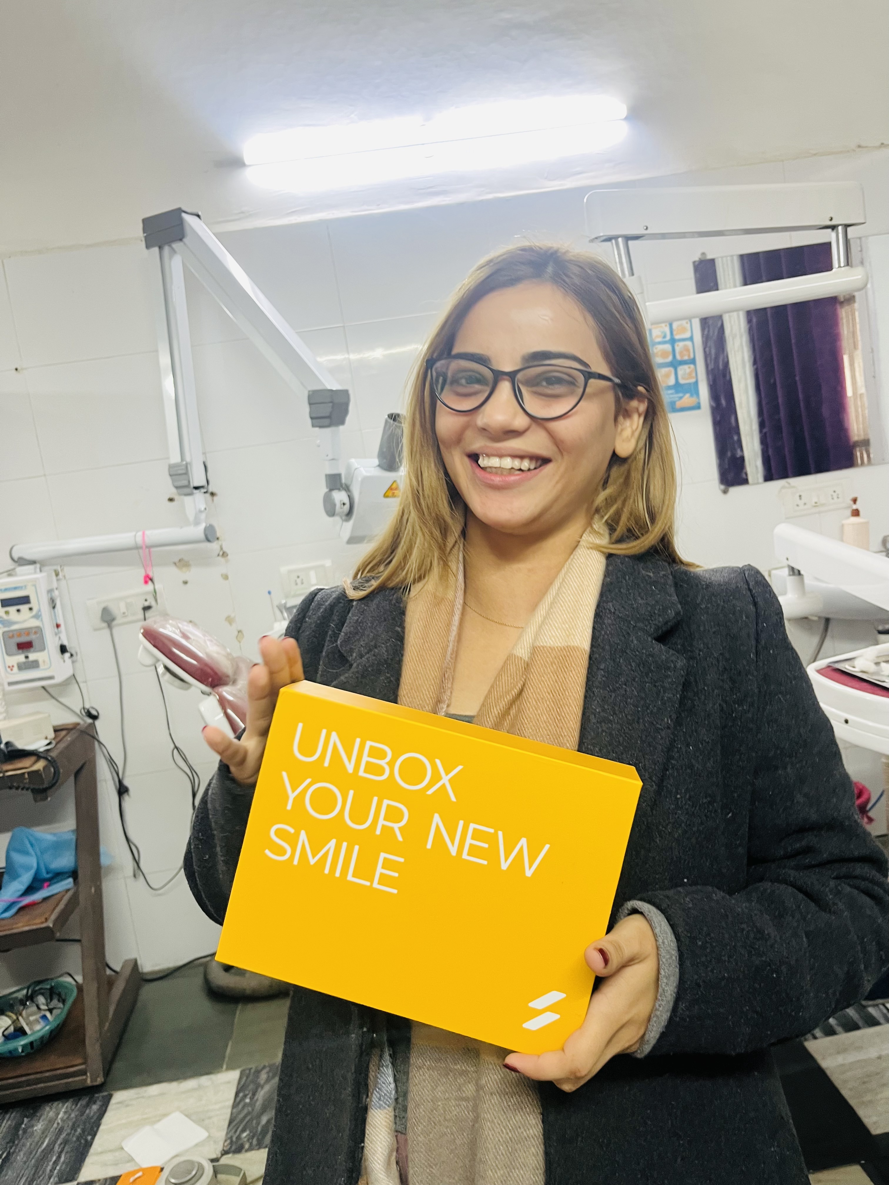 Happy dental client at Dental Ville holding a new smile sign